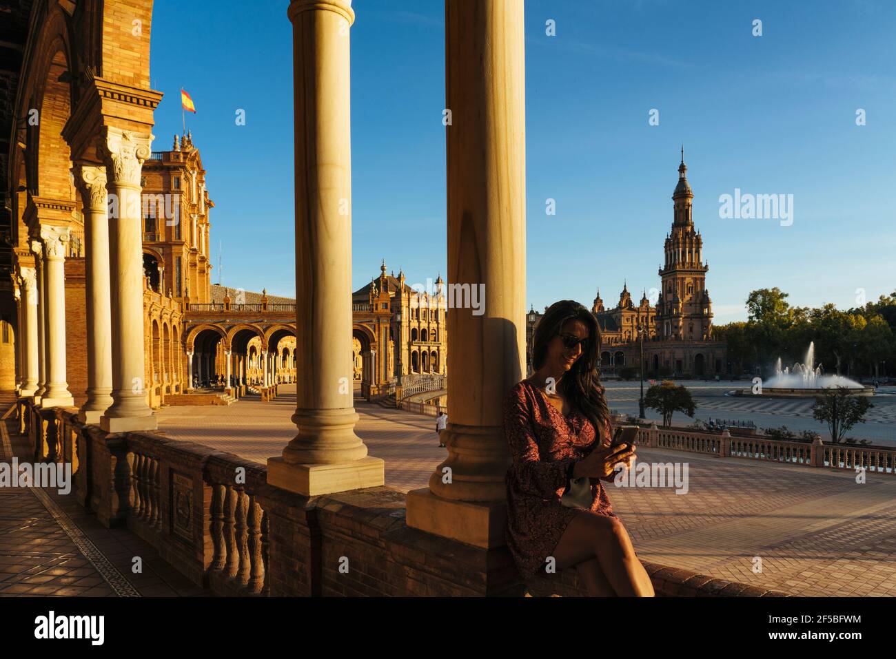 Donna turista che si presenta con smartphone in Piazza di Spagna di Siviglia, Spagna Foto Stock