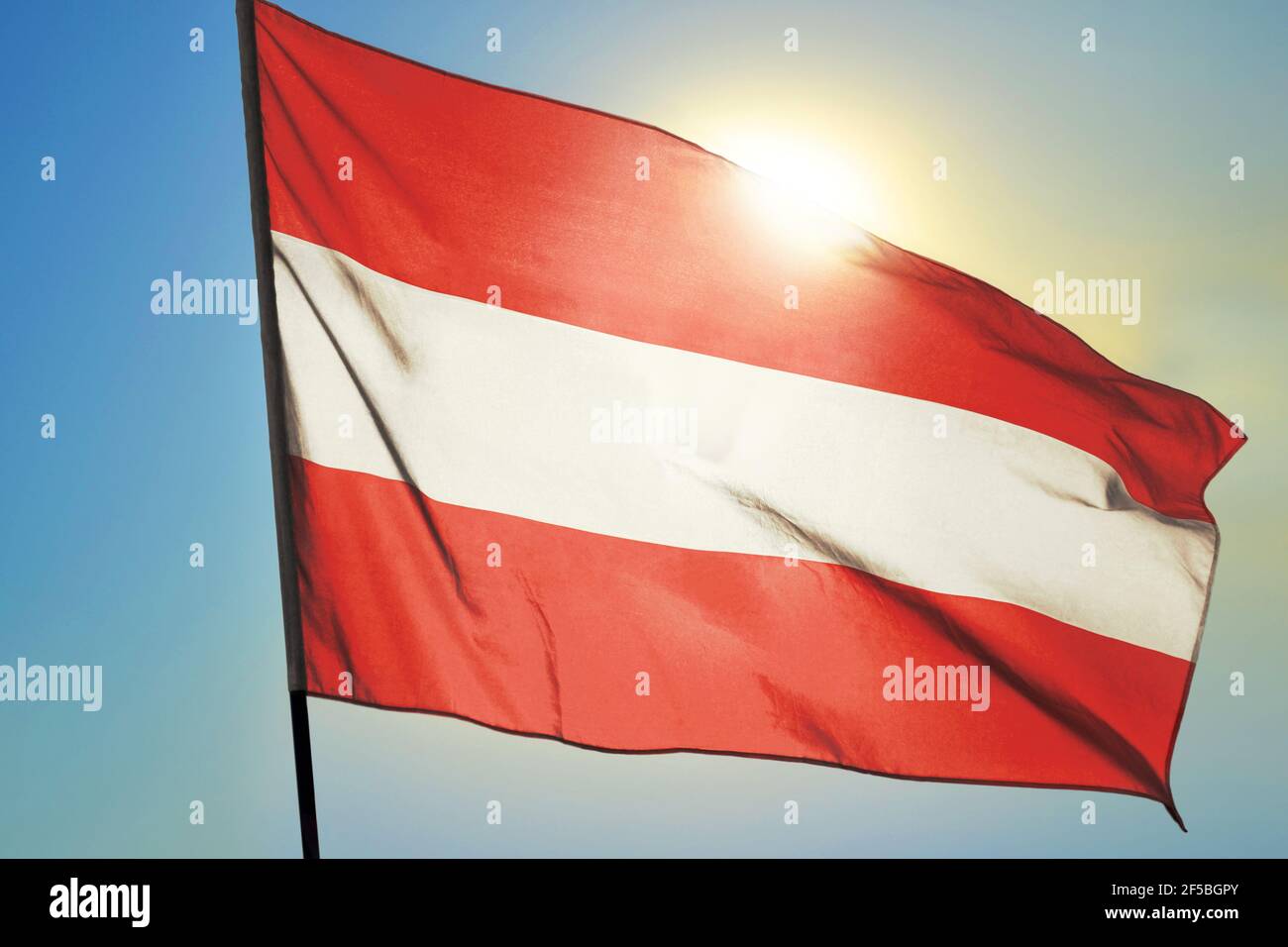 Bandiera austriaca che sventola sul vento davanti al sole Foto Stock