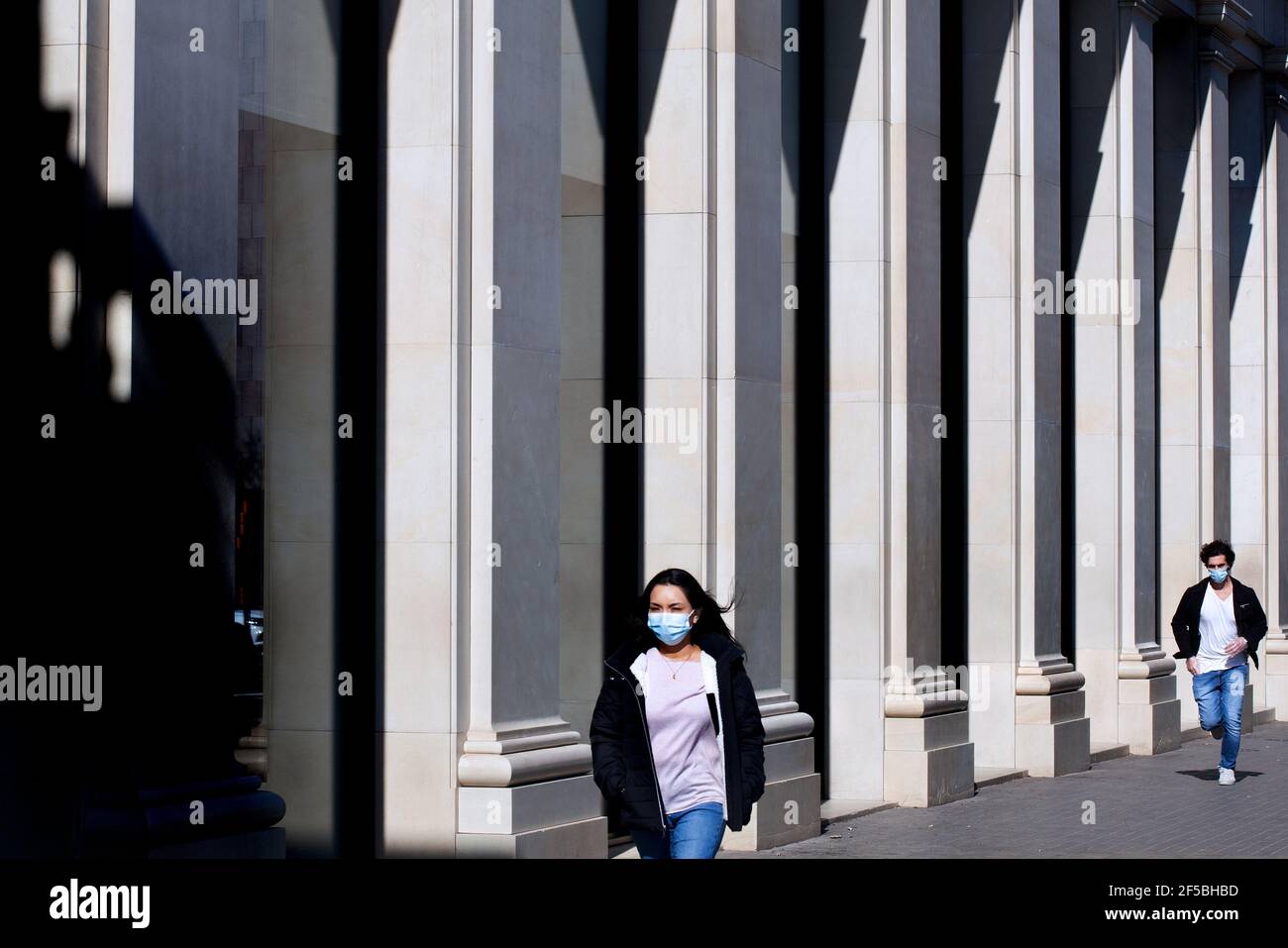 Una giovane donna è perseguita da un uomo per strada. Foto Stock