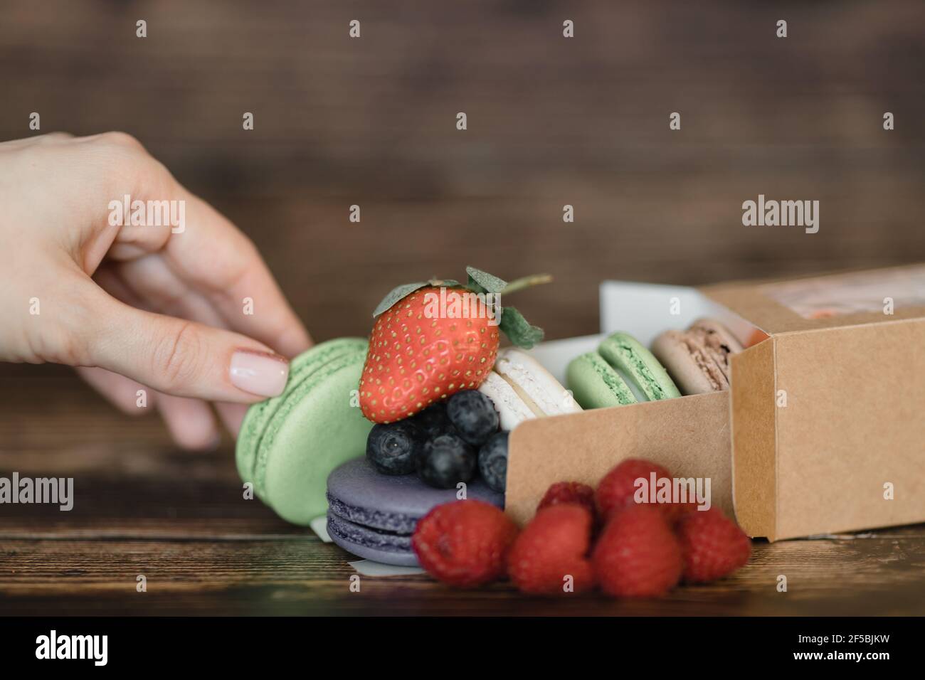La mano della donna presenta le torte di macaroon francesi Foto Stock