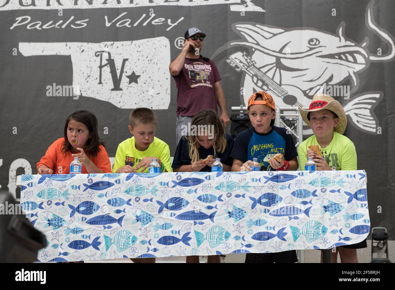 I giovani concorrenti divorano con impazienza il pesce gatto all'annuale gara di noodling per bambini dell'Okie Noodling Tournament's Children's Eating a Paul's Valley, Oklahoma. Foto Stock