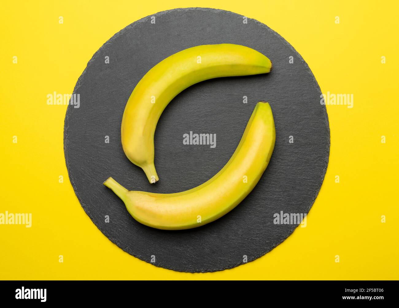 due banane su una piastra di pietra nera Foto Stock