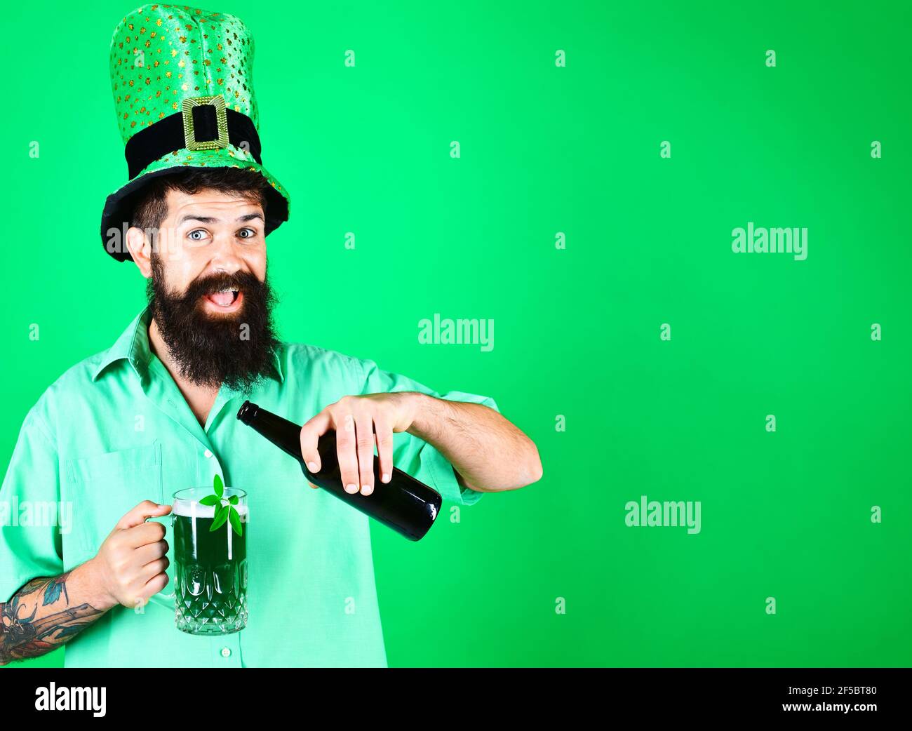 San Patrizio giorno. L'uomo sorridente bearded nel cappello di leprechaun versa la birra in vetro. Foto Stock