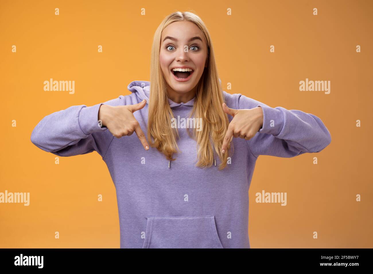 Emozionato europeo carino ragazza bionda capelli sorridenti aperti bocca divertente dire guardare verso il basso verso il basso incredibile fresco nuovo prodotto Foto Stock