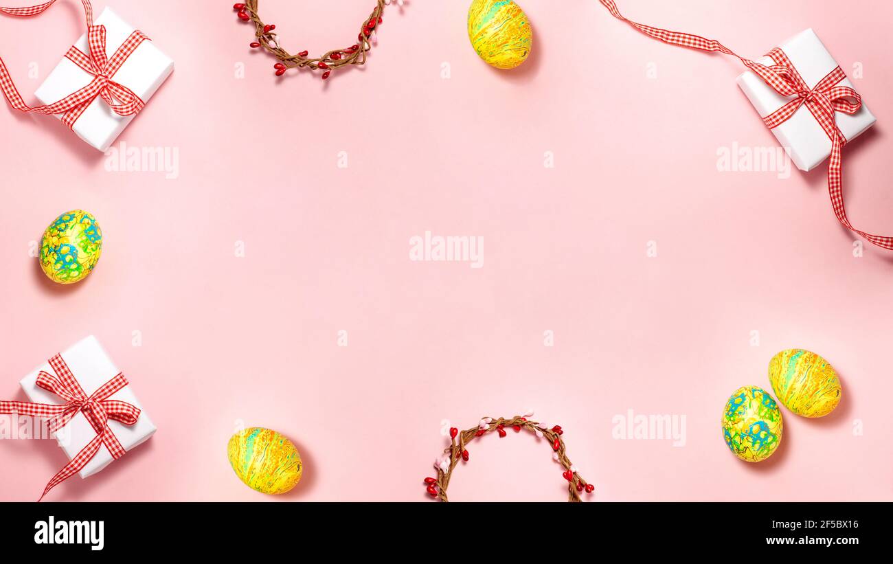 Modello banner di uova di Pasqua verde e giallo, scatola regalo di carta bianca con arco regalo rosso e corona tessuta con gemme rosse e rosa sulla parte posteriore rosa brillante Foto Stock
