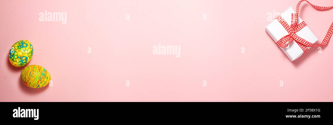 Modello banner di uova verdi e gialle pasquali e bianche confezione regalo di carta con prua regalo rossa su rosa brillante Sfondo piatto Lay vista dall'alto bufale pasquale Foto Stock