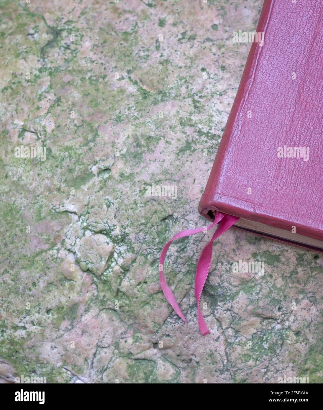 Libro di copertina in pelle marrone rosso con nastro preferito. Sopra la superficie della pietra. Vista piatta. Foto Stock