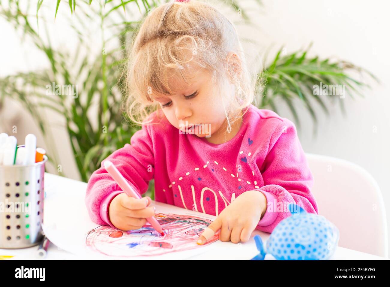 Sotto quarantena divertimento. La pittura della ragazza piccola durante l'epidemia del coronavirus e facendo i compiti. Stile di vita sotto virus corona. Foto Stock
