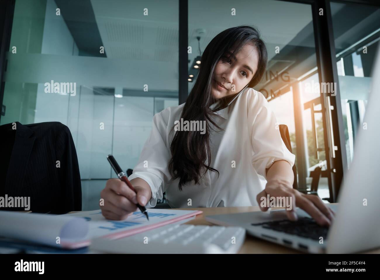 Donna di affari che tiene la mano la penna e che punta al lavoro finanziario della documentazione con diagramma della rete finanziaria. Foto Stock