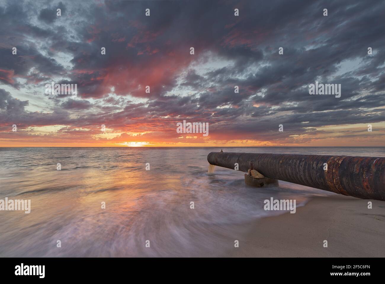 Tramonto sull'oceano e scarico della tempesta di drenaggio Foto Stock