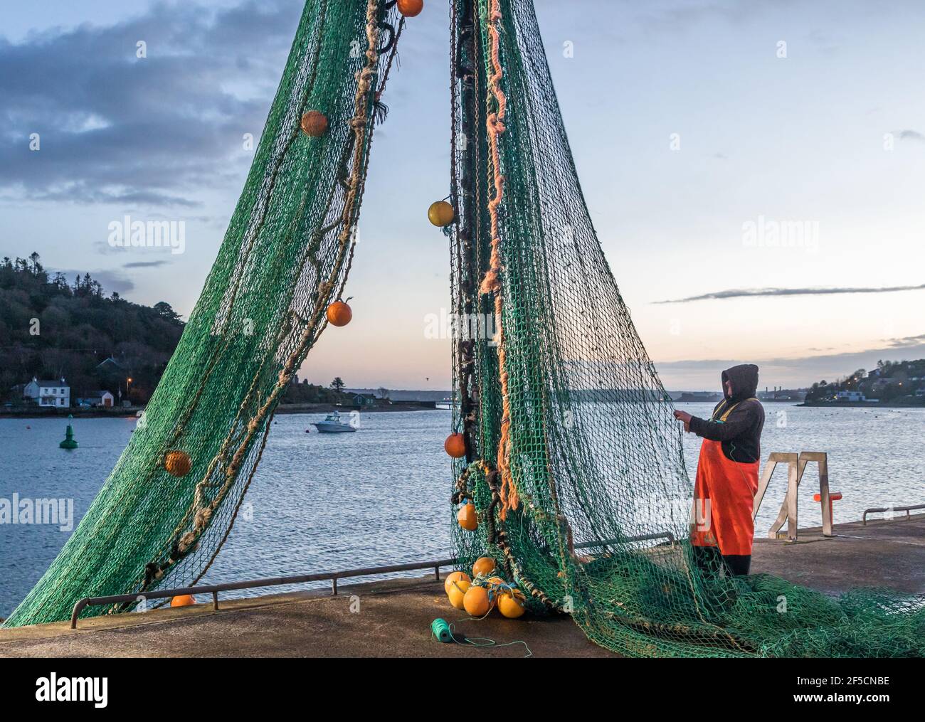 Crosshaven, Cork, Irlanda. 26 Marzo 2021. Il pescatore Jacko Murphy controlla e ripara le reti del peschereccio Buddy M all'alba sul molo di Crosshaven, Co. Cork, Irlanda. - credito; credito: David Creedon/Alamy Live News Foto Stock