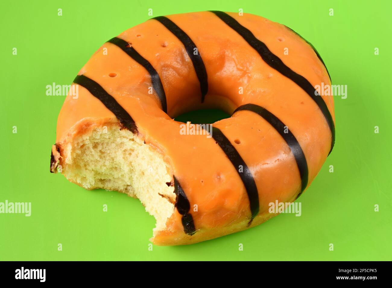 Ciambella arancione ricoperta di glassa rosa isolata su sfondo verde. Foto Stock