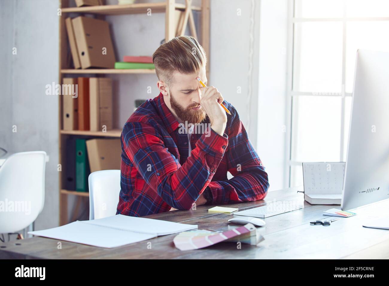 Un giovane che pensa a un nuovo progetto sul posto di lavoro Foto Stock