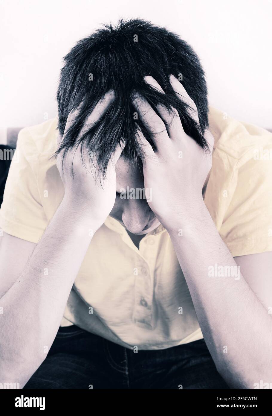 Tone Foto di Sad Young Man sul lettino dentro La camera Foto Stock