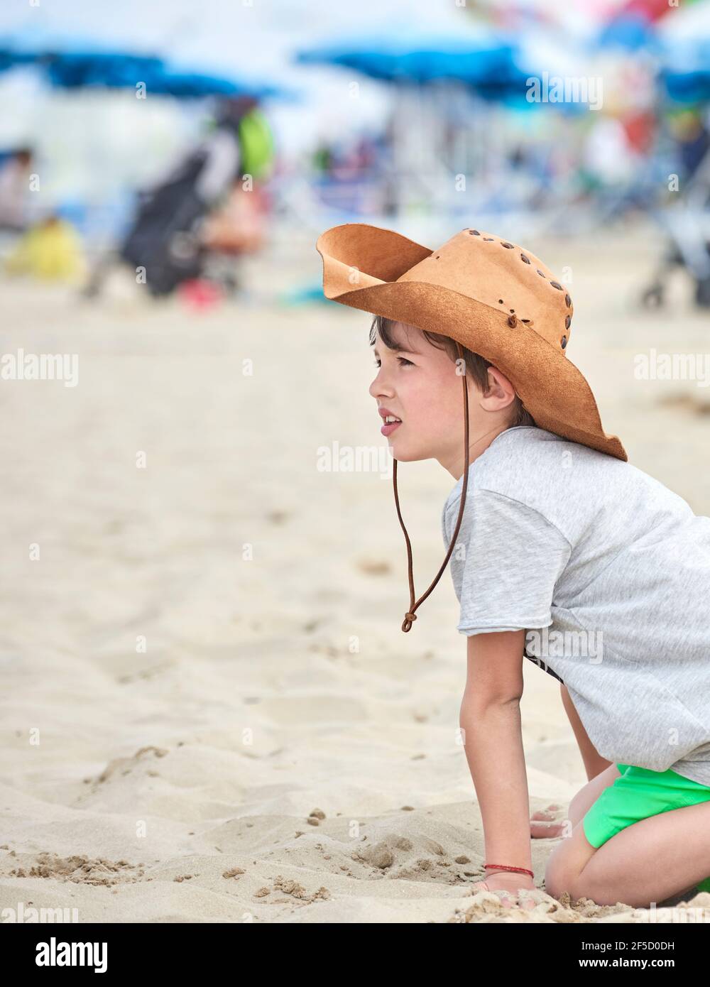 Bambino felice con cappello di cuoio del cowboy che gioca con la sabbia.  Primo piano di un bambino sorridente con cappello da cowboy, sulla spiaggia  vicino al mare Foto stock - Alamy