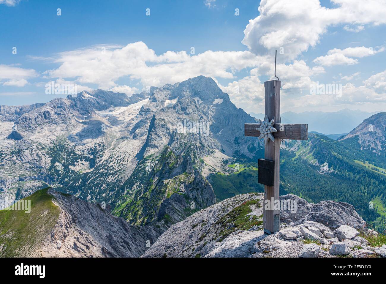 Una croce in cima alla montagna con i monti Dachstein e i suoi ghiacciai sullo sfondo Foto Stock