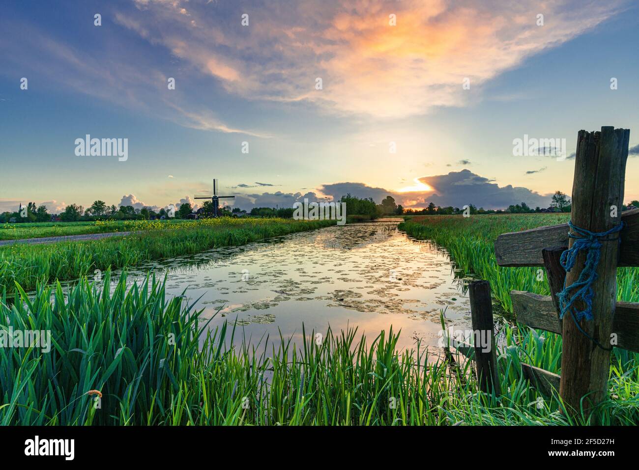 Sunsrise nel cuore verde olandese (Groene Hart) su praterie e via d'acqua con un mulino a vento tradizionale Foto Stock