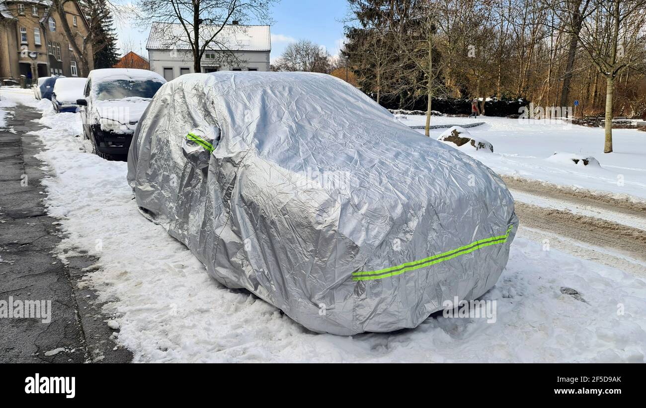 Auto sotto telone su strada innevata in inverno, Germania Foto Stock