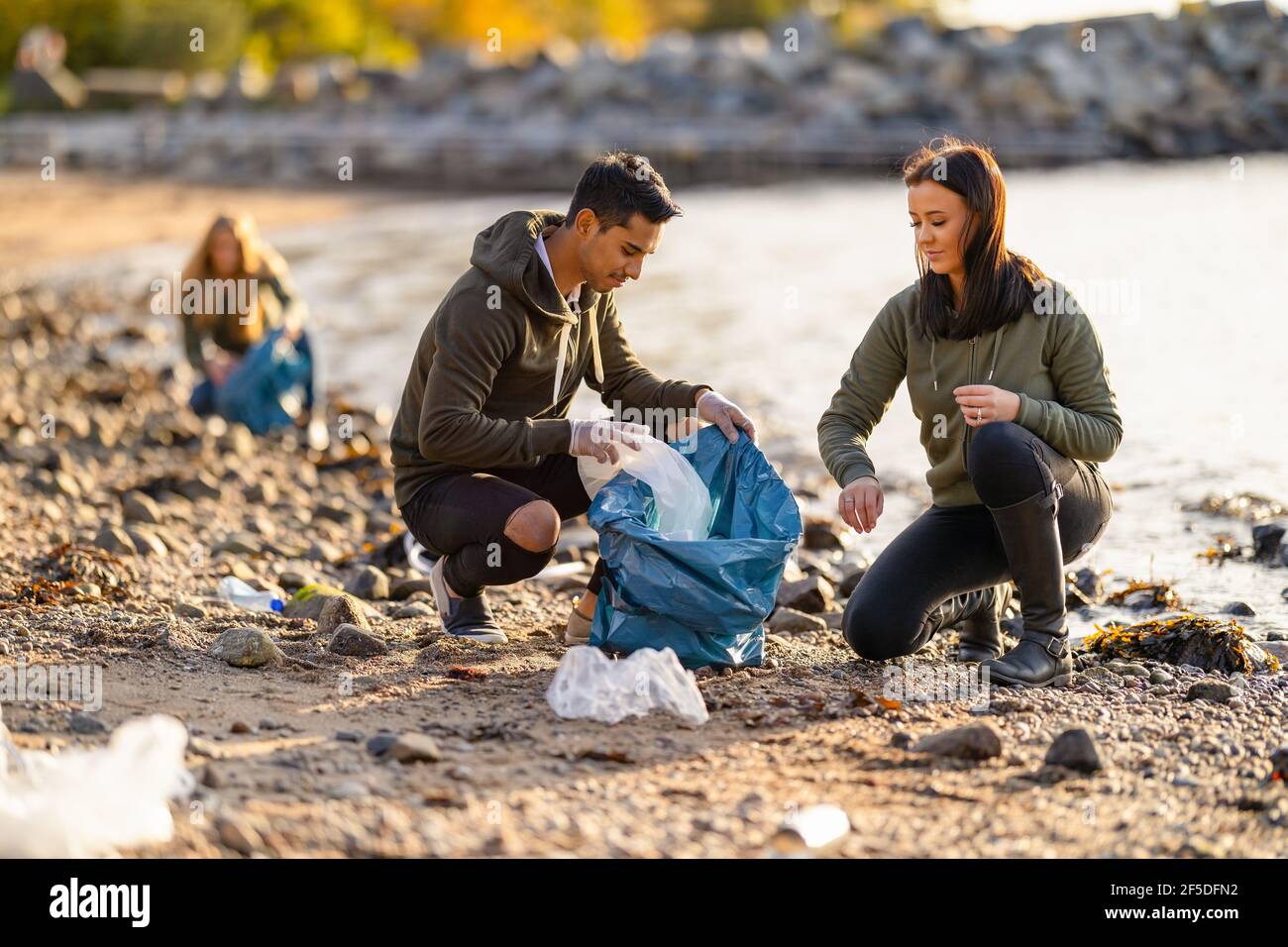 Team di volontari che lavorano duramente per raccogliere rifiuti di plastica in spiaggia Foto Stock