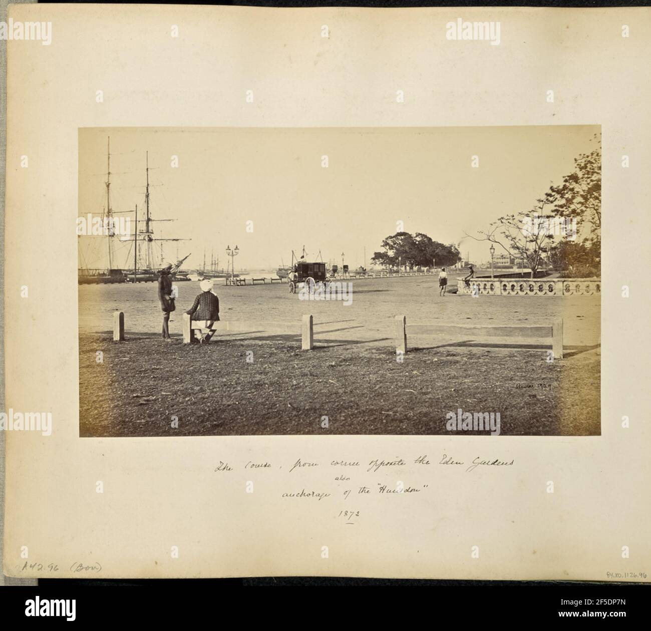 Calcutta; 'The Strand' vicino all'Eden Gardens. Vista di un incrocio tra Strand Road e Gostha Paul Sarani presso l'Eden Gardens cricket Grounds lungo il fiume Hooghly. Le navi ormeggiate possono essere viste lungo il fiume sulla sinistra, e una carrozza trainata da cavalli si trova al centro dell'intersezione. Un uomo si siede su una ringhiera in primo piano accanto a un uomo che si trova accanto a lui. Una parete di pietra decorata con un motivo circolare perforato corre intorno all'angolo sul lato lontano della strada con un uomo seduto su di esso. (Recto, image) in basso a destra, scritto a mano in negativo: '1727' (recto, mount) in basso a sinistra, ha Foto Stock