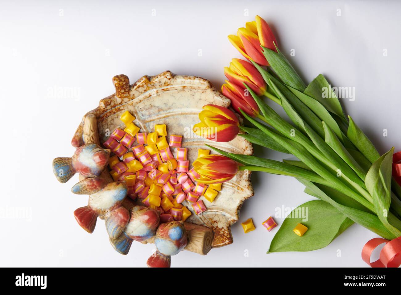 tulipani rossi e gialli su sfondo bianco e a. piatto con uccelli con rosso Foto Stock