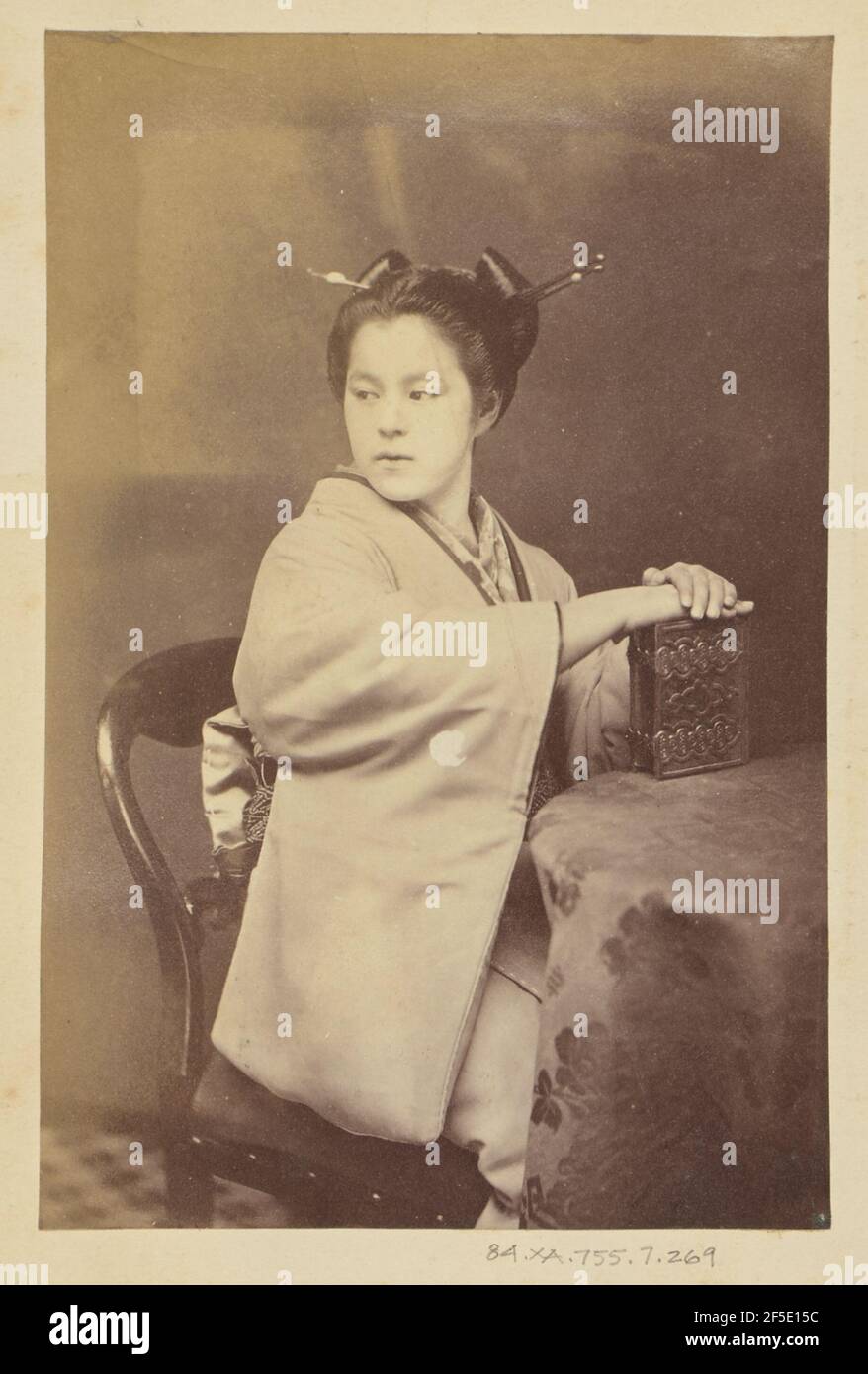 Donna giapponese seduta che tiene un album cartes-de-visite a un tavolo. Foto Stock