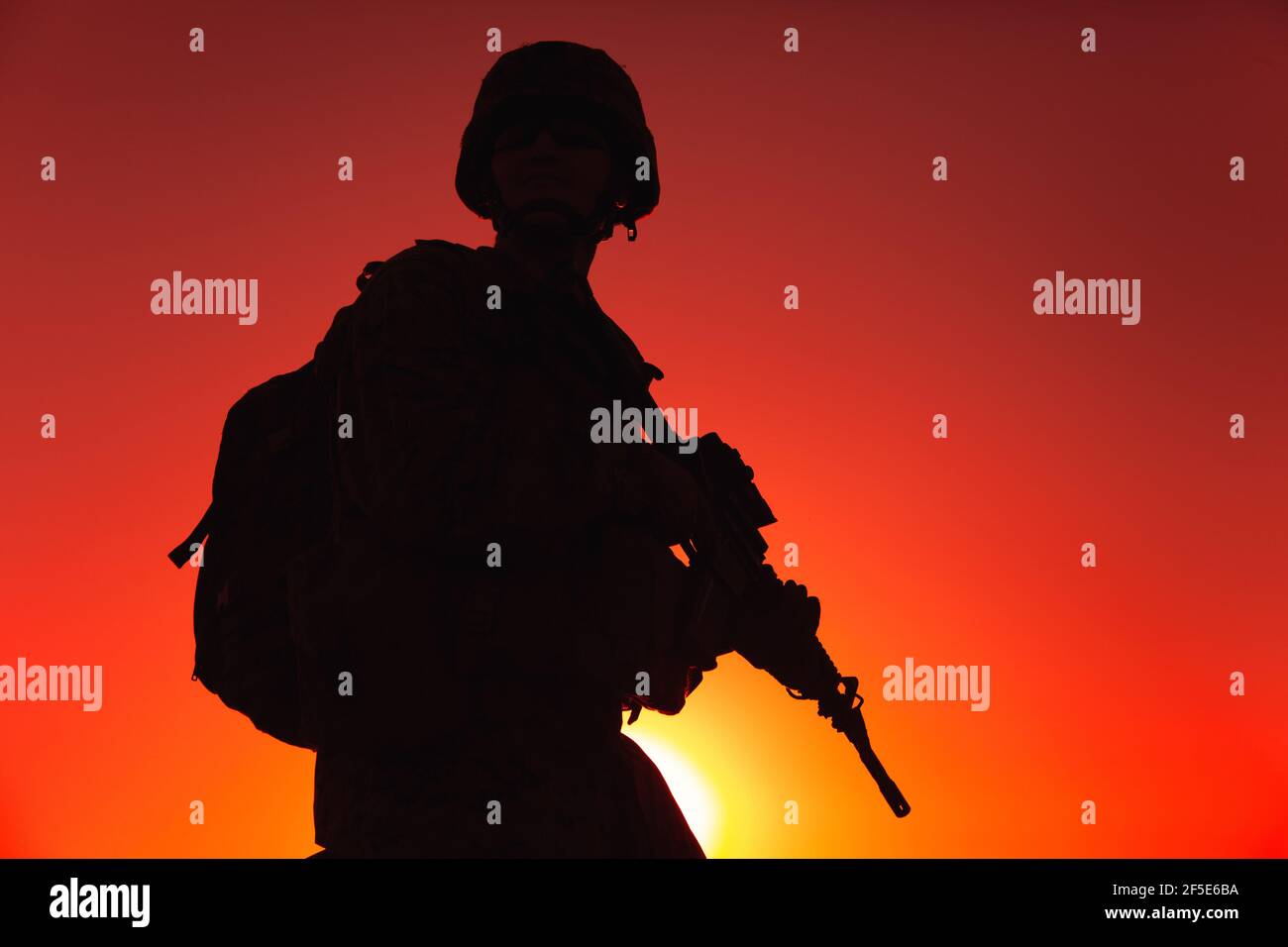 Silhouette di fucile militare in casco e munizioni, con zaino tattico, camminando con fucile di servizio sullo sfondo del cielo del tramonto. Combattente contro le forze terroristiche che marciano in missione notturna Foto Stock