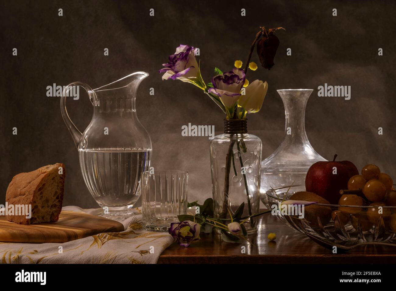 Un tavolo di legno è allestito con cibo, bevande e un vaso di vetro con fiori Foto Stock