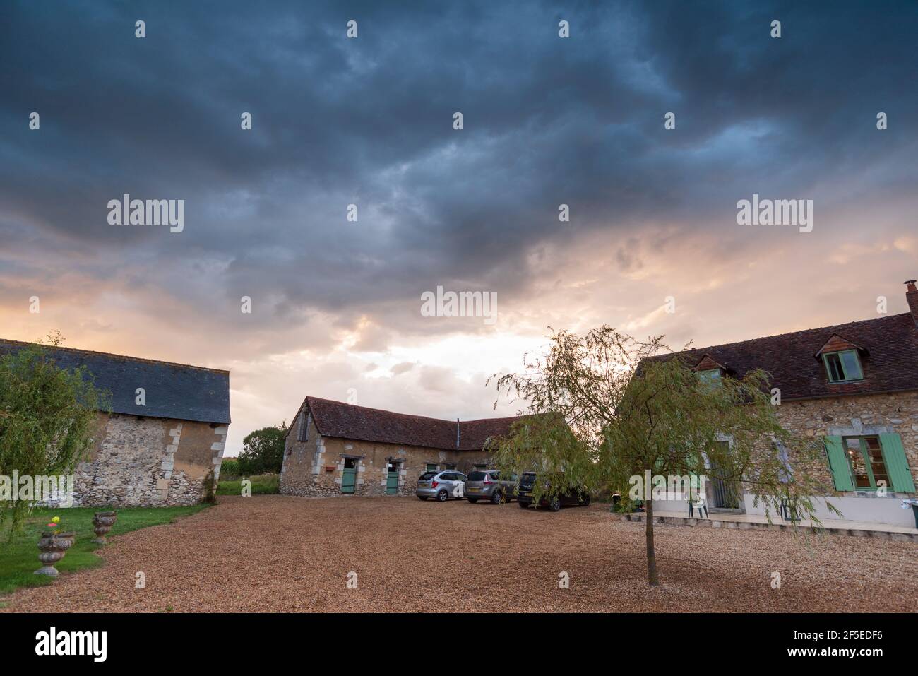 Tempesta nuvole al tramonto su una rustica casa colonica francese. Foto Stock