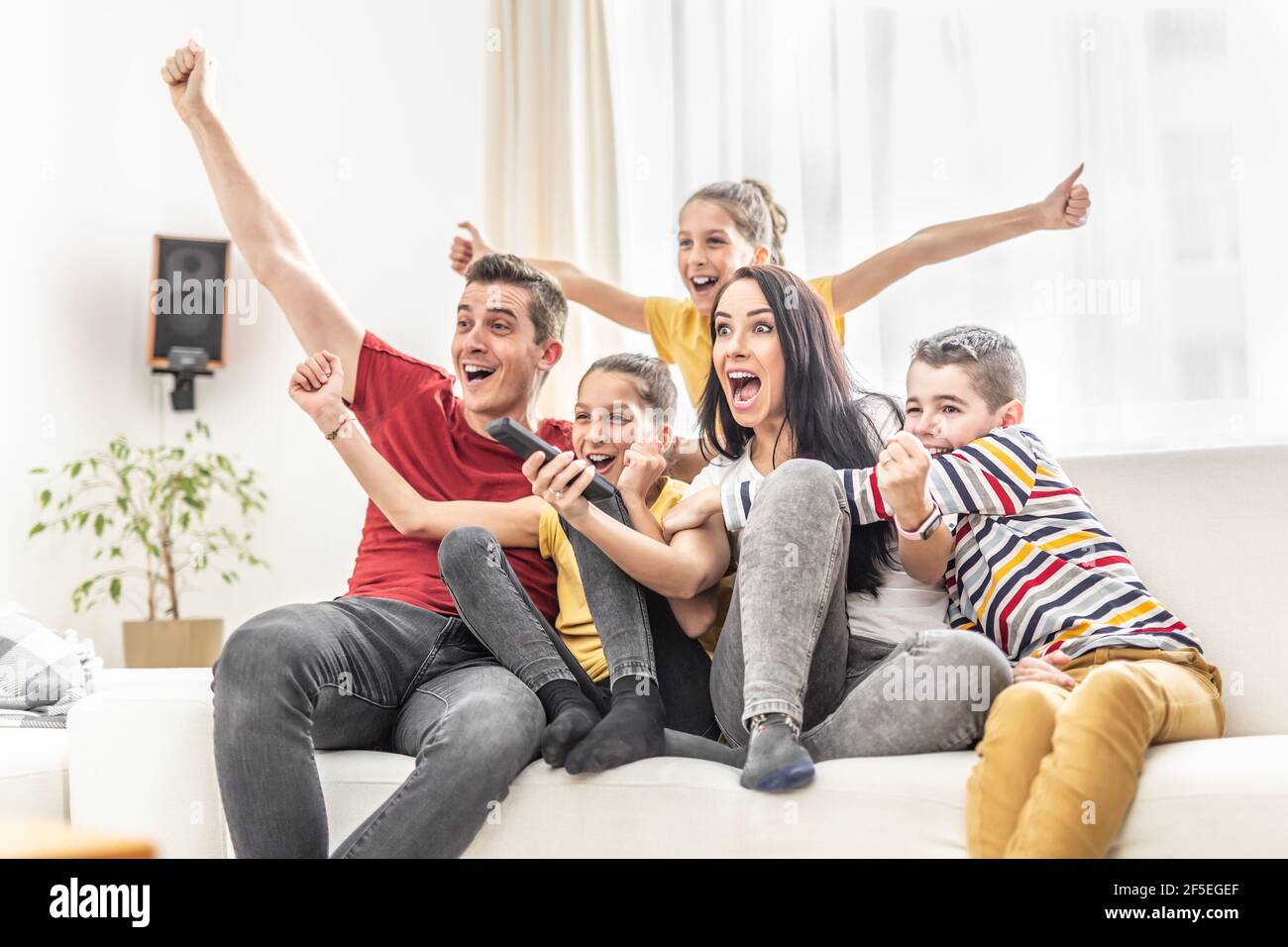 Una famiglia entusiasta di cinque amici a casa che guarda gli sport TV Foto Stock