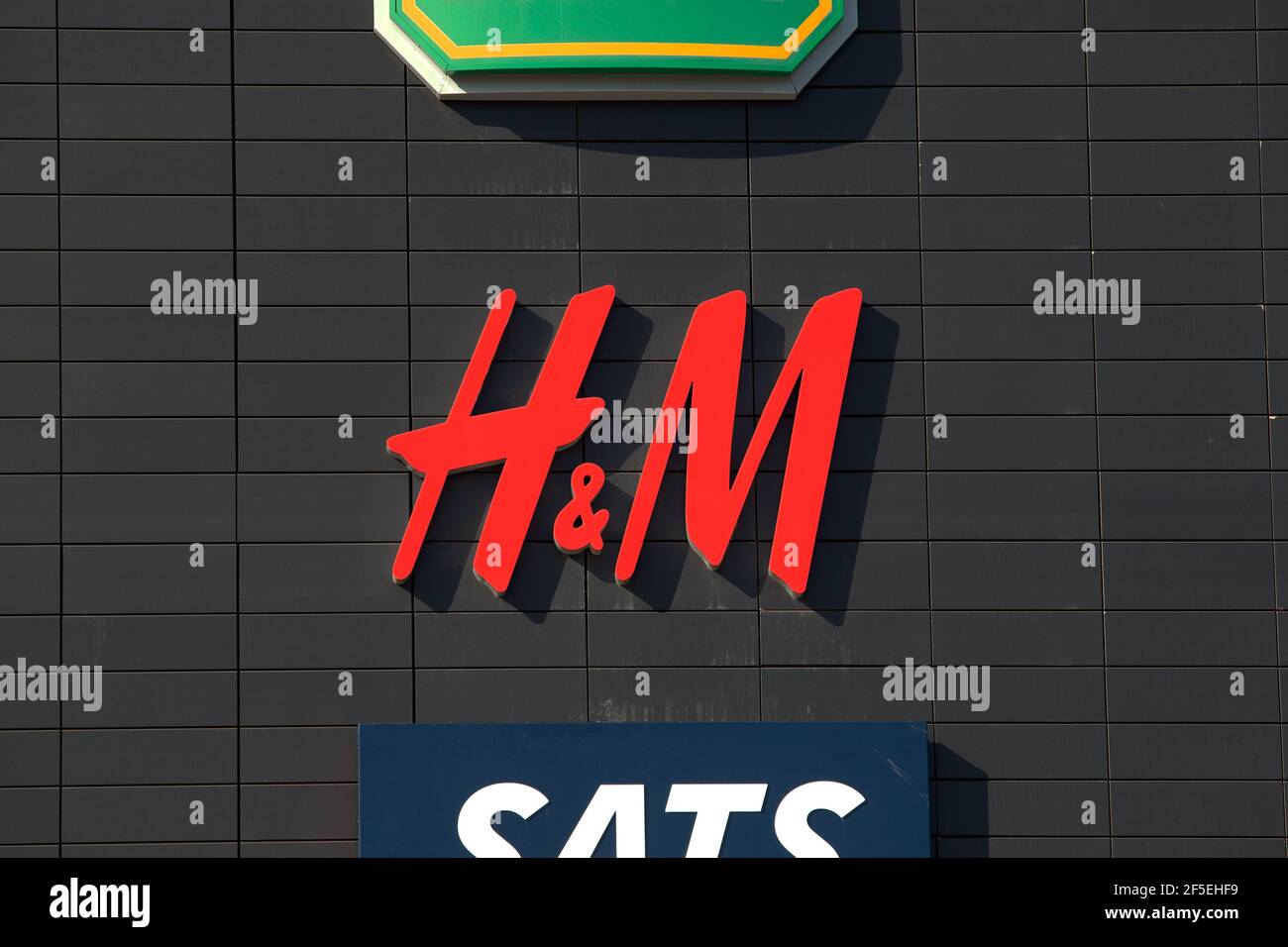 Stoccolma, Svezia - 25 marzo 2021: H&M (Hennes & Mauritz) firma su una facciata nera con altri due loghi parzialmente visibili per simboleggiare la marca retail Foto Stock
