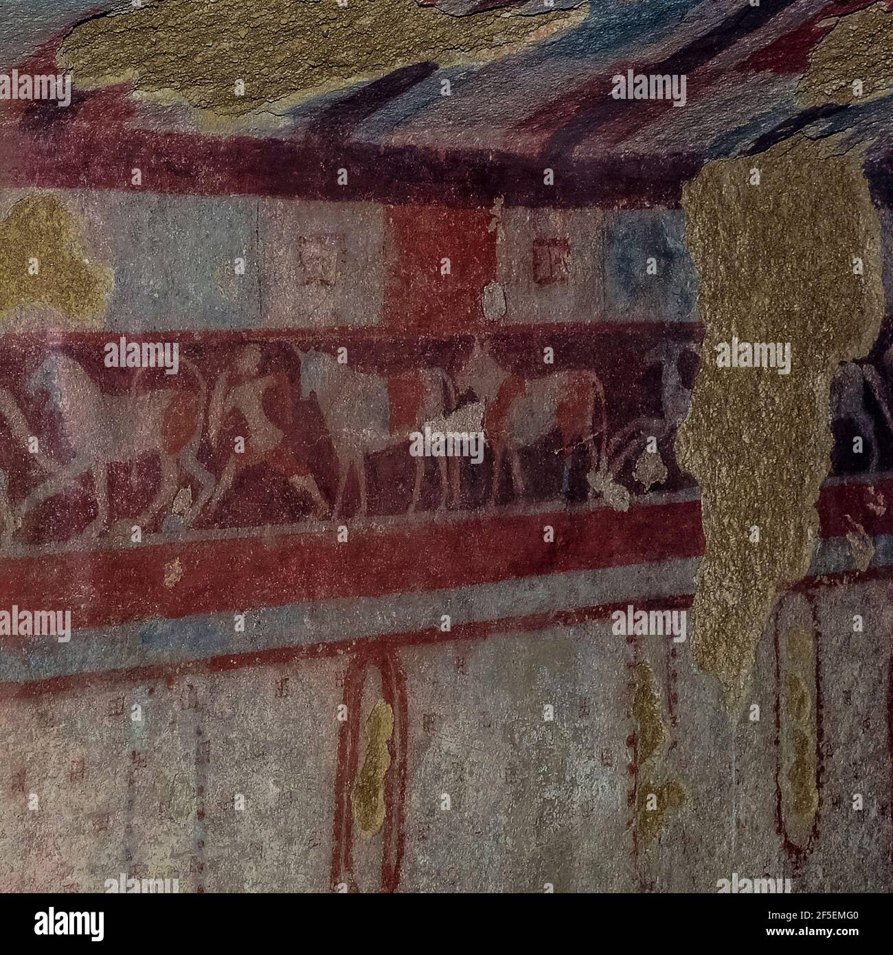 Un fregio con tori, leoni, stracci, cani, cavalieri e guerrieri corre lungo le pareti affrescate della Tomba del Cacciatore, risalente a 2,500 anni fa, nella necropoli di Monterozzi dell'antica Tarchuna etrusca o Tarchna a Tarquinia, Lazio, Italia. La tomba è dipinta per assomigliare all'interno di una tenda di caccia, con un velo trasparente sotto il colorato tetto scacchiera che lascia il cacciatore defunto vedere i cervi nutrirsi in un paesaggio pastorale. Altri dipinti funerari di Monterozzi raffigurano la vita etrusca di tutti i giorni, tra cui banchetti con musica e balli, atletica e riti funebri. Foto Stock