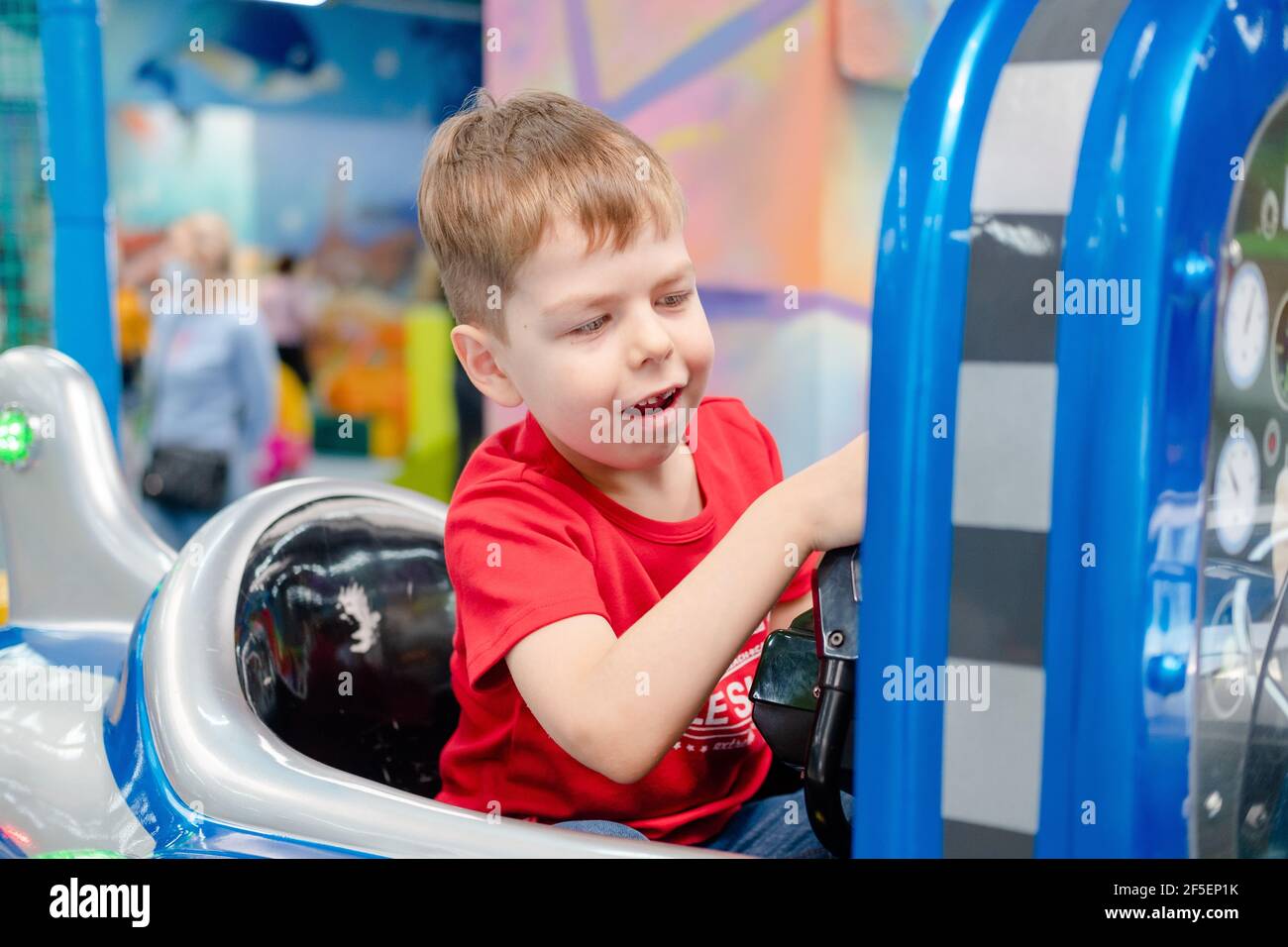 il ragazzino gioca sulle corse. Sala giochi per bambini. Il bambino è seduto in un aereo. Weekend attivo con bambini Foto Stock