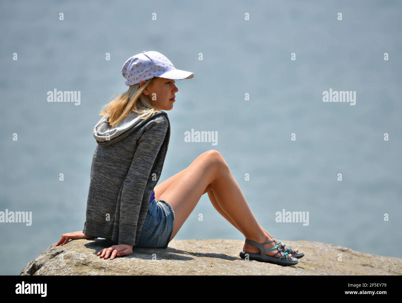 Paesaggio con una giovane bionda che indossa un cappello da baseball bianco  sulle rocce di Morro Bay a San Luis Obispo, California Foto stock - Alamy