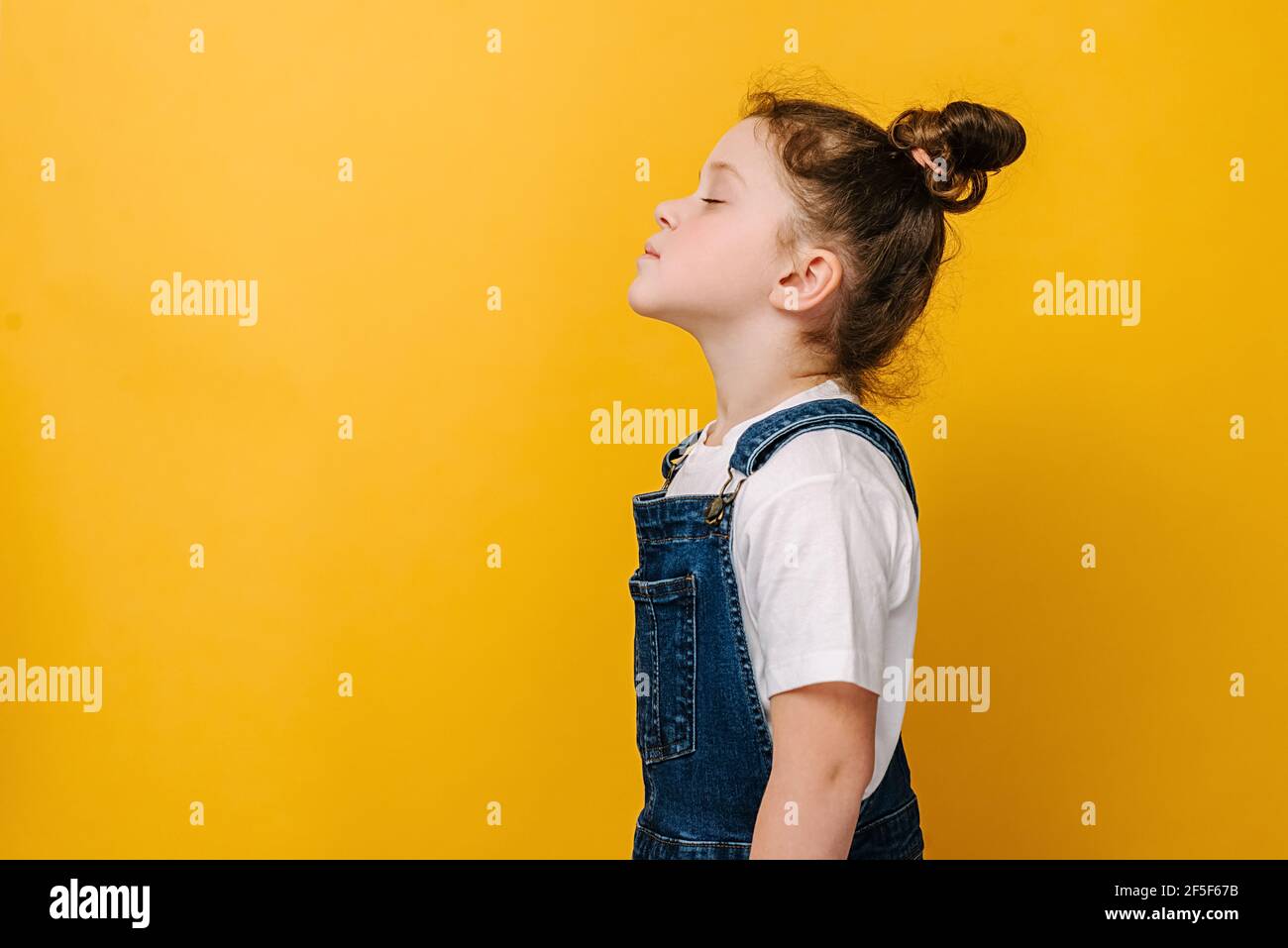 Profilo vista laterale di felice dolce poco preschool ragazza fare respiro profondo godetevi l'aria fresca o sognando riempirsi di energia sensazione di sano buon concetto Foto Stock