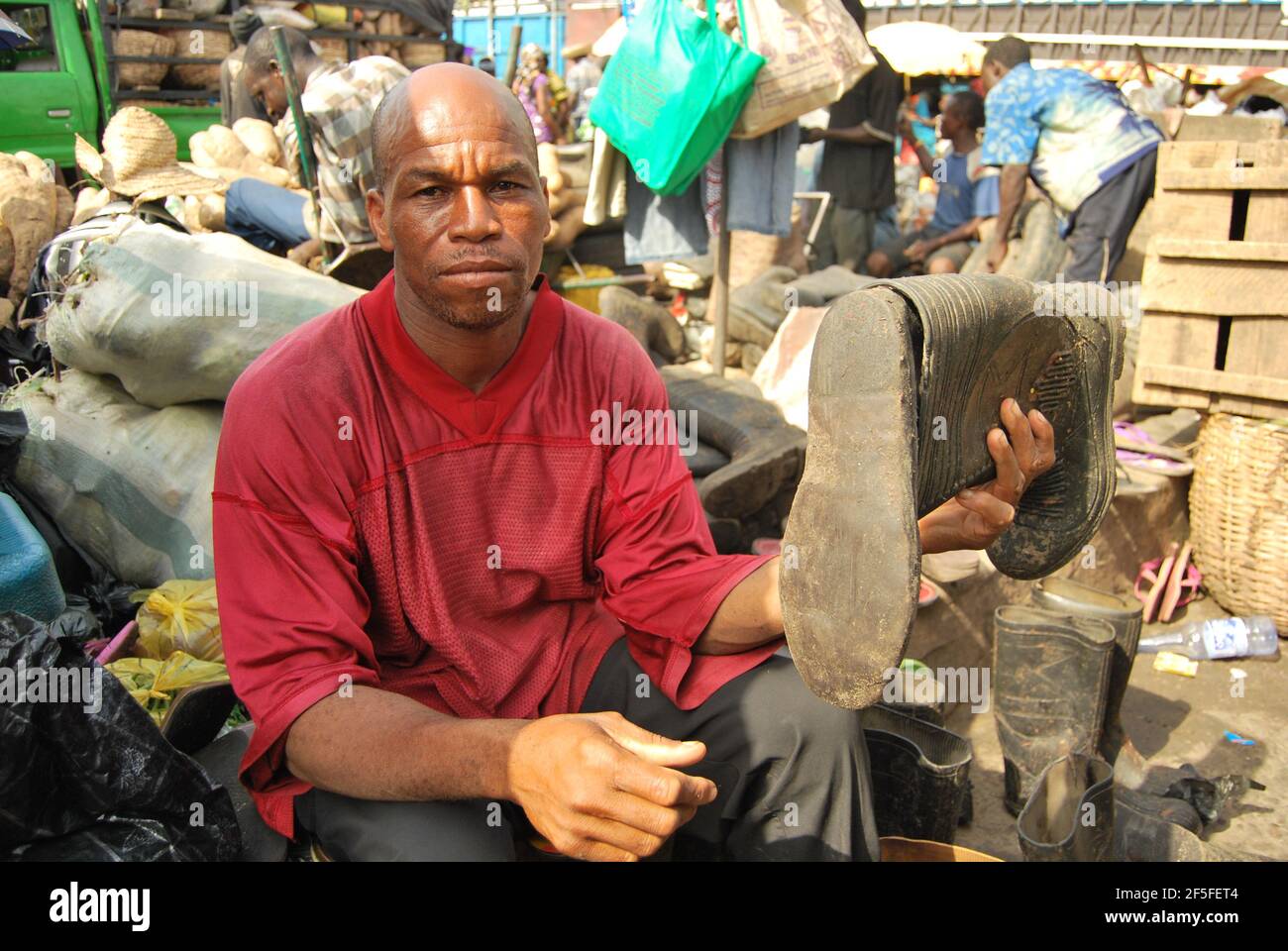 Un uomo mostra stivali da pioggia in affitto al mercato Mile 12, Lagos Foto  stock - Alamy