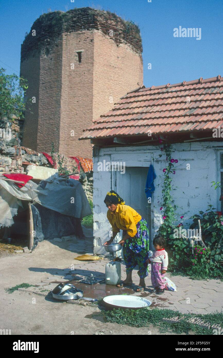 Villaggio donna e bambino lavaggio con antica torre dietro Iznik Turchia. Foto Stock