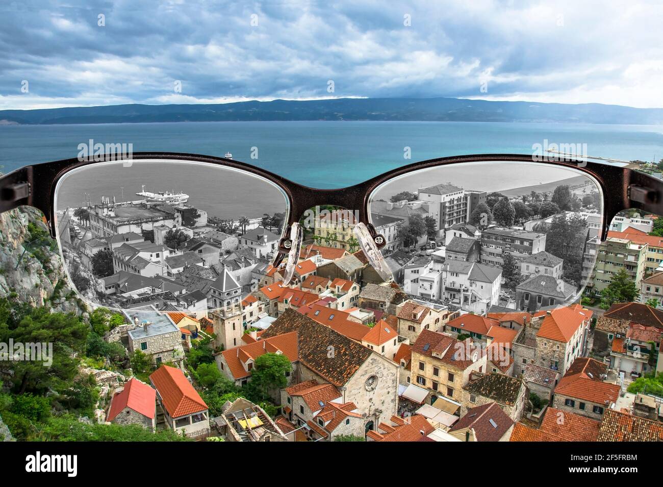 Guardando attraverso i vetri ai tetti desaturati e il mare nella città croata focalizzato in occhiali da donna. Cecità del colore. Percezione del mondo durante la depressione. Foto Stock