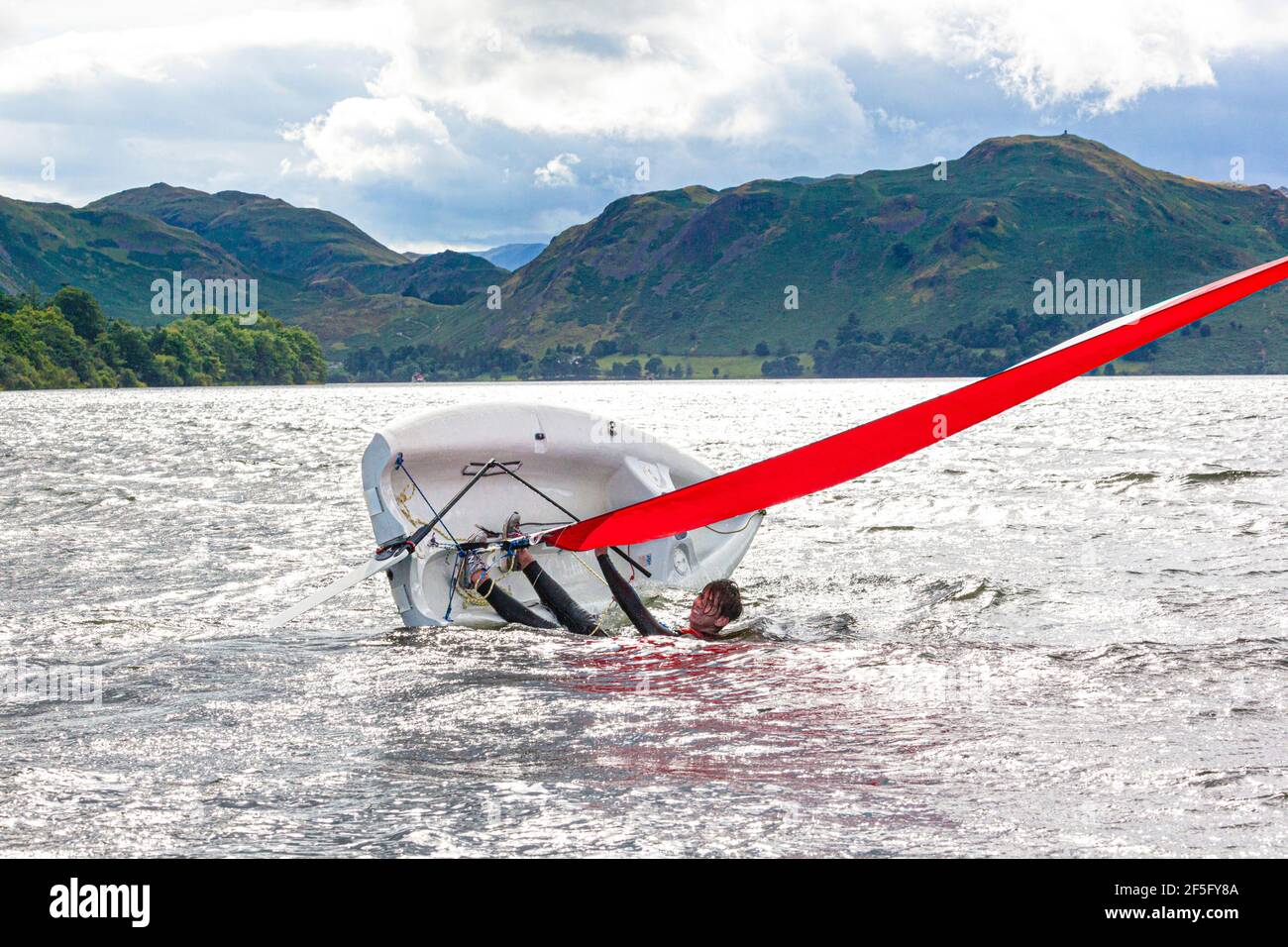 The English Lake District - Sailing on Ullswater, Cumbria UK - UN giovane uomo che taglia un dinghy Foto Stock