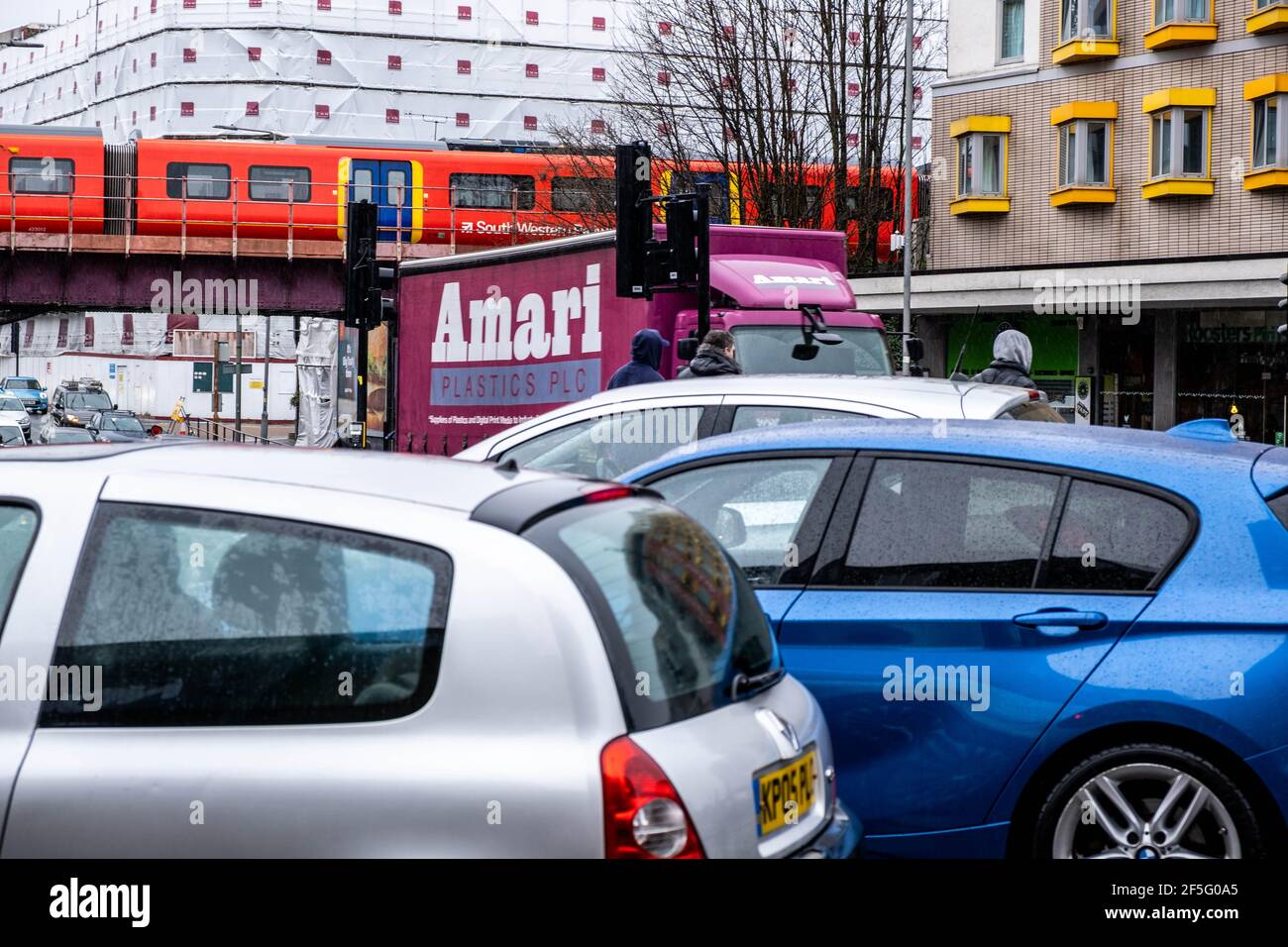 Londra UK, marzo 26 2021, Traffic Jam con un treno ferroviario che attraversa UN ponte stradale di fronte agli edifici alti Foto Stock