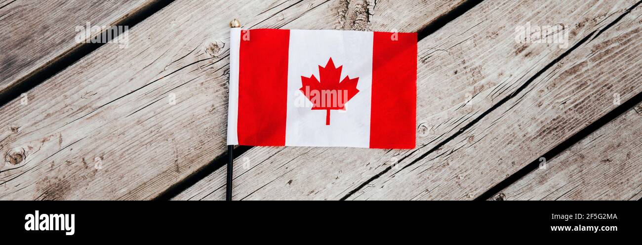 Bandiera canadese rossa con foglia di acero rosso su tavole di legno sfondo all'aperto. Simbolo della bandiera canadese durante la festa nazionale del Canada il 1° luglio. Vie Foto Stock