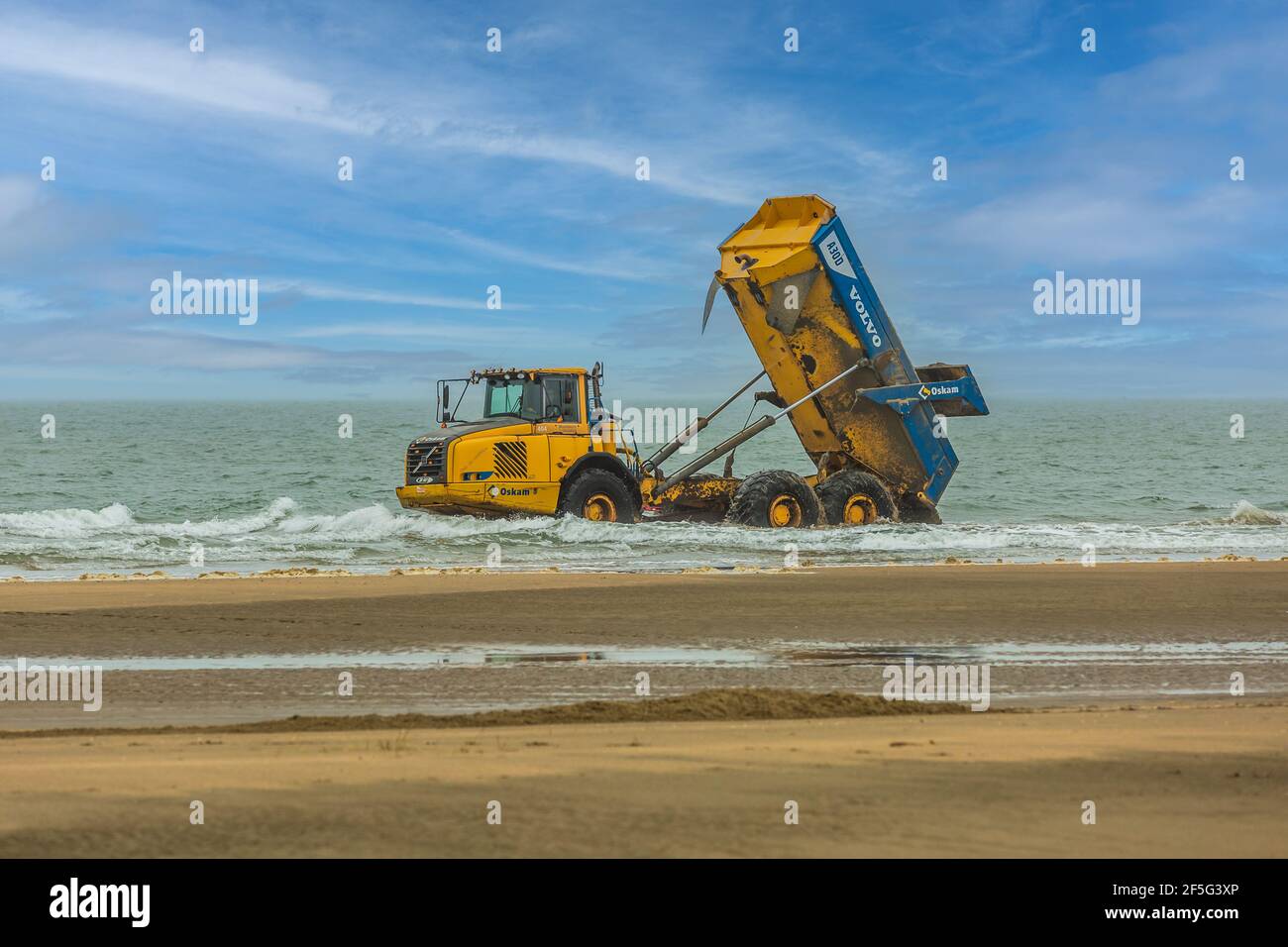 IJmuiderslag, IJmuiden, provincia dell'Olanda del Nord, Paesi Bassi, 25 marzo 2021: Volvo Dumper Volvo A30D discarica la sabbia nel surf del Mare del Nord Foto Stock