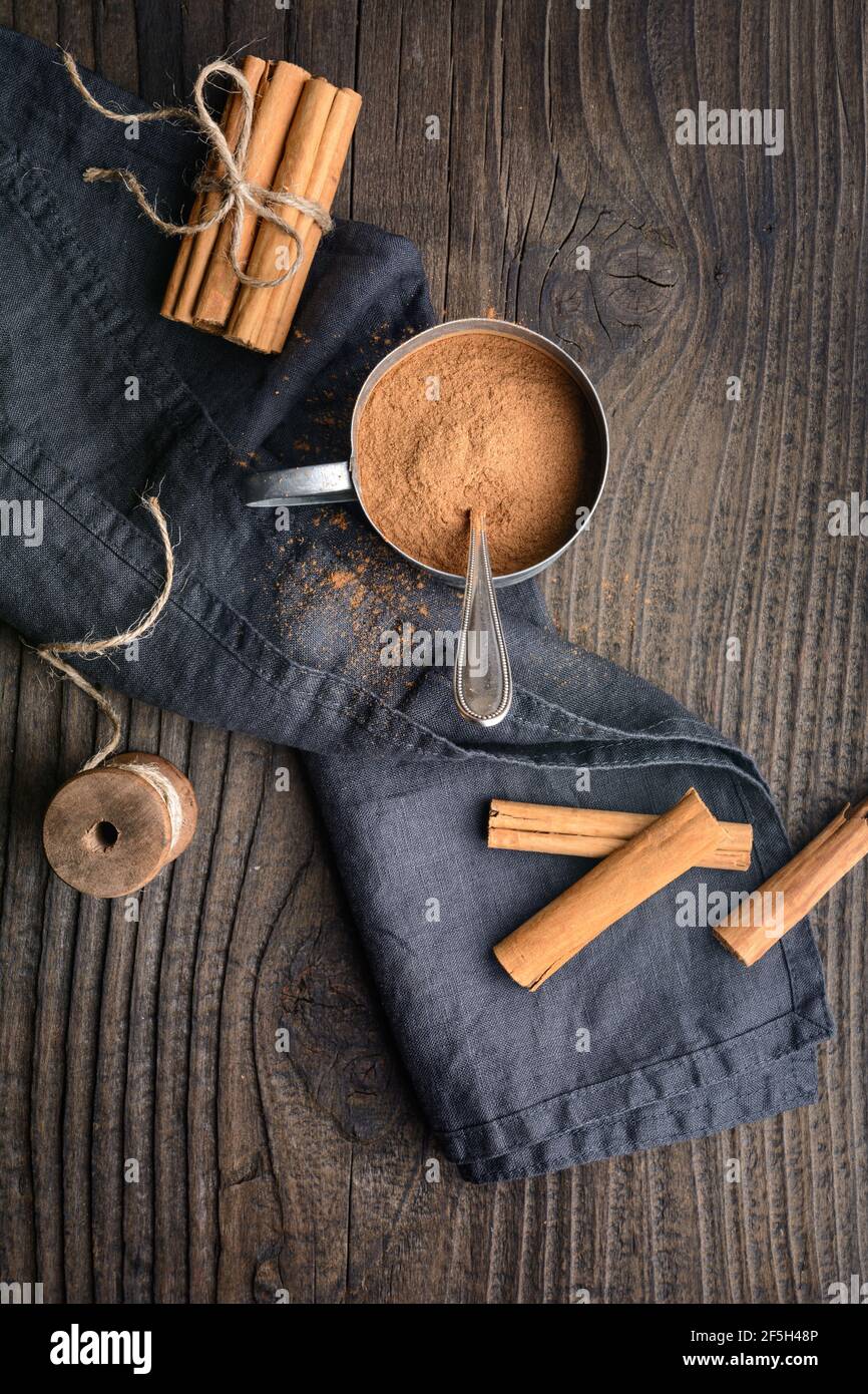 Condimento alimentare sano con proprietà medicinali, bastoncini di cannella Ceylon e polvere in un vaso su sfondo di legno Foto Stock