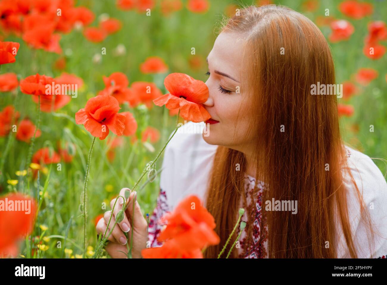 Ucraino bella Donna in ricamo tradizionale in campo papaveri ritratto esterno. Raccolta papaveri e fiore di mais in campo estivo. Pop in fiore Foto Stock
