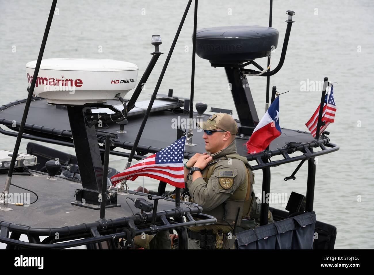 Granjeno, Texas USA, 26 marzo 2021. Texas Department of Public Safety Trooper attende un gruppo di senatori repubblicani degli Stati Uniti a bordo di una gunboat appositamente allestita per un giro sul Rio Grande River a sud di Mission alla fine di un vortice tour del Texas meridionale. I senatori videro un centro di lavorazione dei migranti sovraffollato a Donna e un cadavere che galleggiava nel fiume a nord del Parco di Anzalduas. Credit: Bob Daemmrich/Alamy Live News Foto Stock
