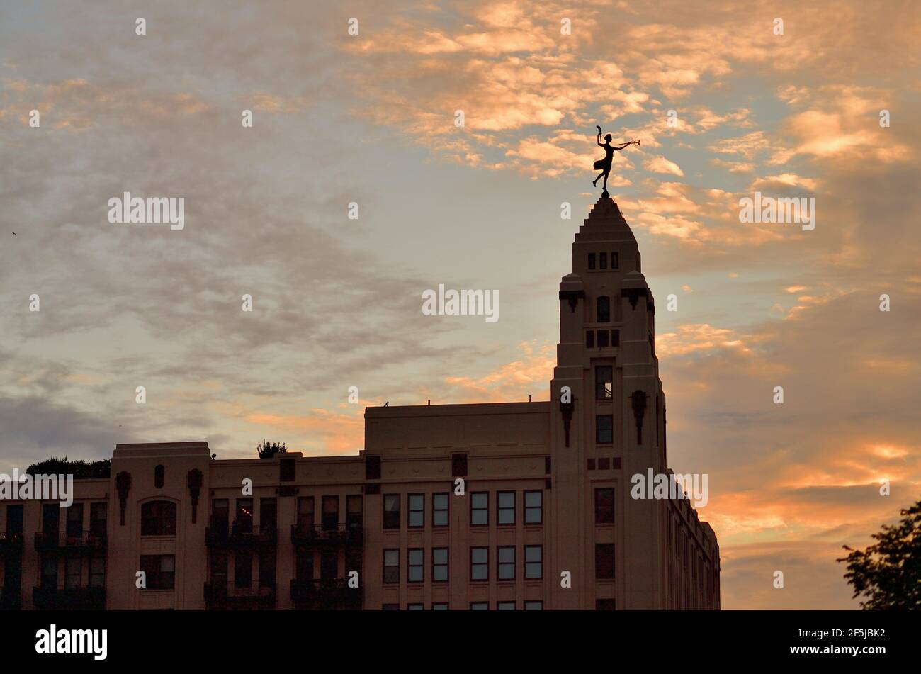 Chicago, Illinois, Stati Uniti. La statua in cima all'edificio amministrativo del complesso di Montgomery Ward è illuminata come una silhouette dal sole che tramonta. Foto Stock