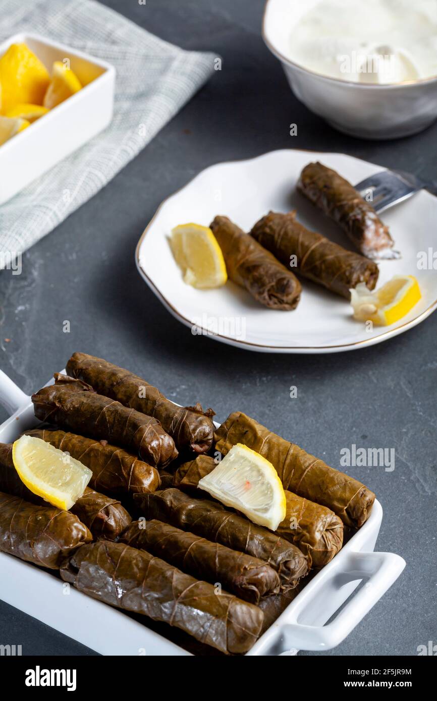 Lo Yaprak sarmasi è un piatto tradizionale turco, fatto da involtini di riso ripieno di foglie d'uva. Servito in vassoio di porcellana con fette di limone e una tazza di Foto Stock