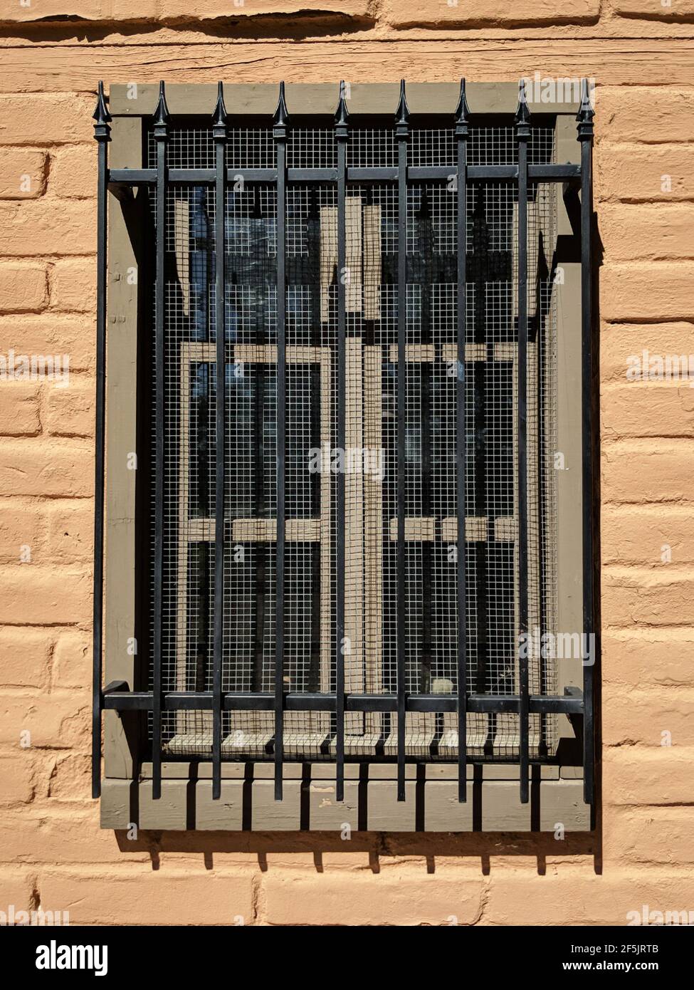 Una finestra di vecchio adobe con barre ornamentali in ferro. Foto Stock