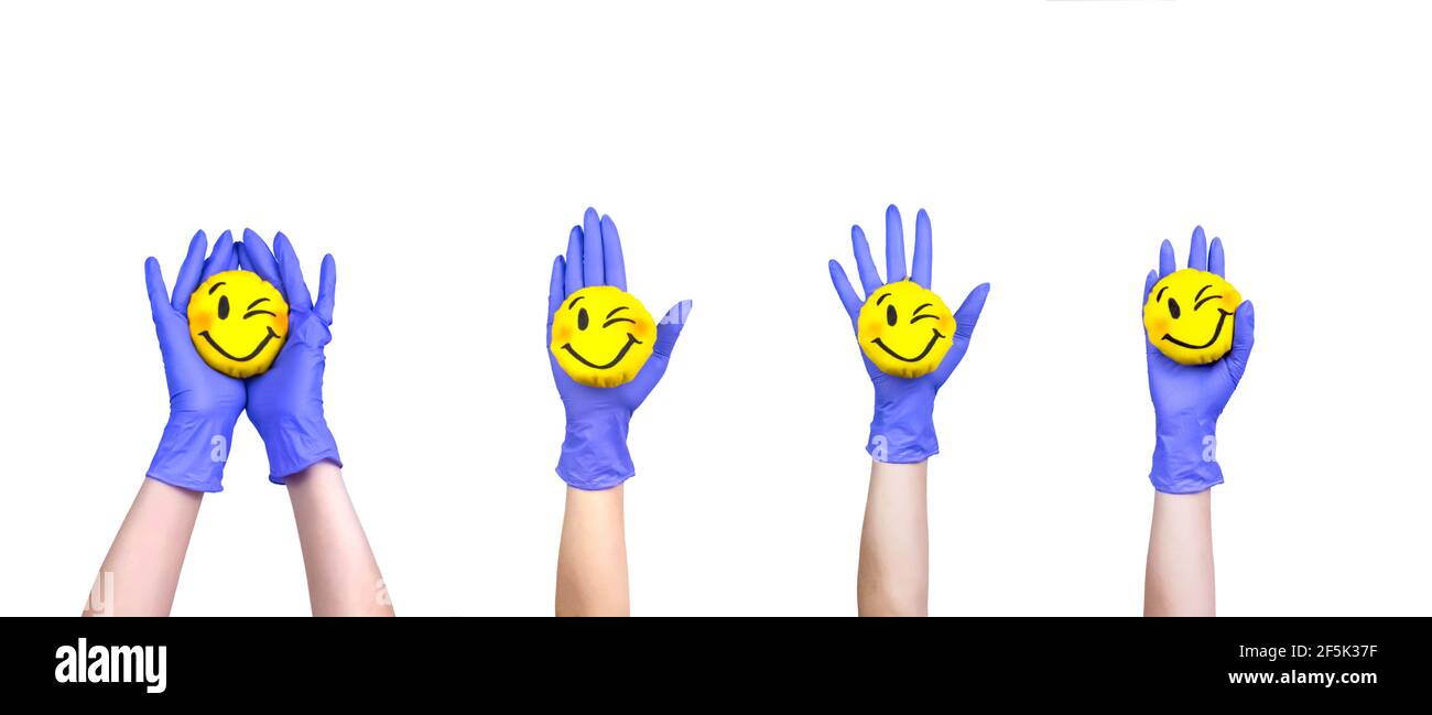 Mani in un medico guanti che tengono il giocattolo sorridente. Buon sorriso nelle nostre mani. Foto Stock