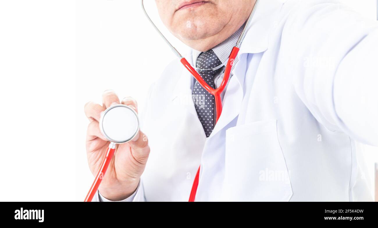 Primo piano di un medico non riconosciuto che tiene lo stetoscopio rosso vicino a un paziente per ascoltare il loro cuore o polmoni. Concetto di medicina e cura del cuore Foto Stock